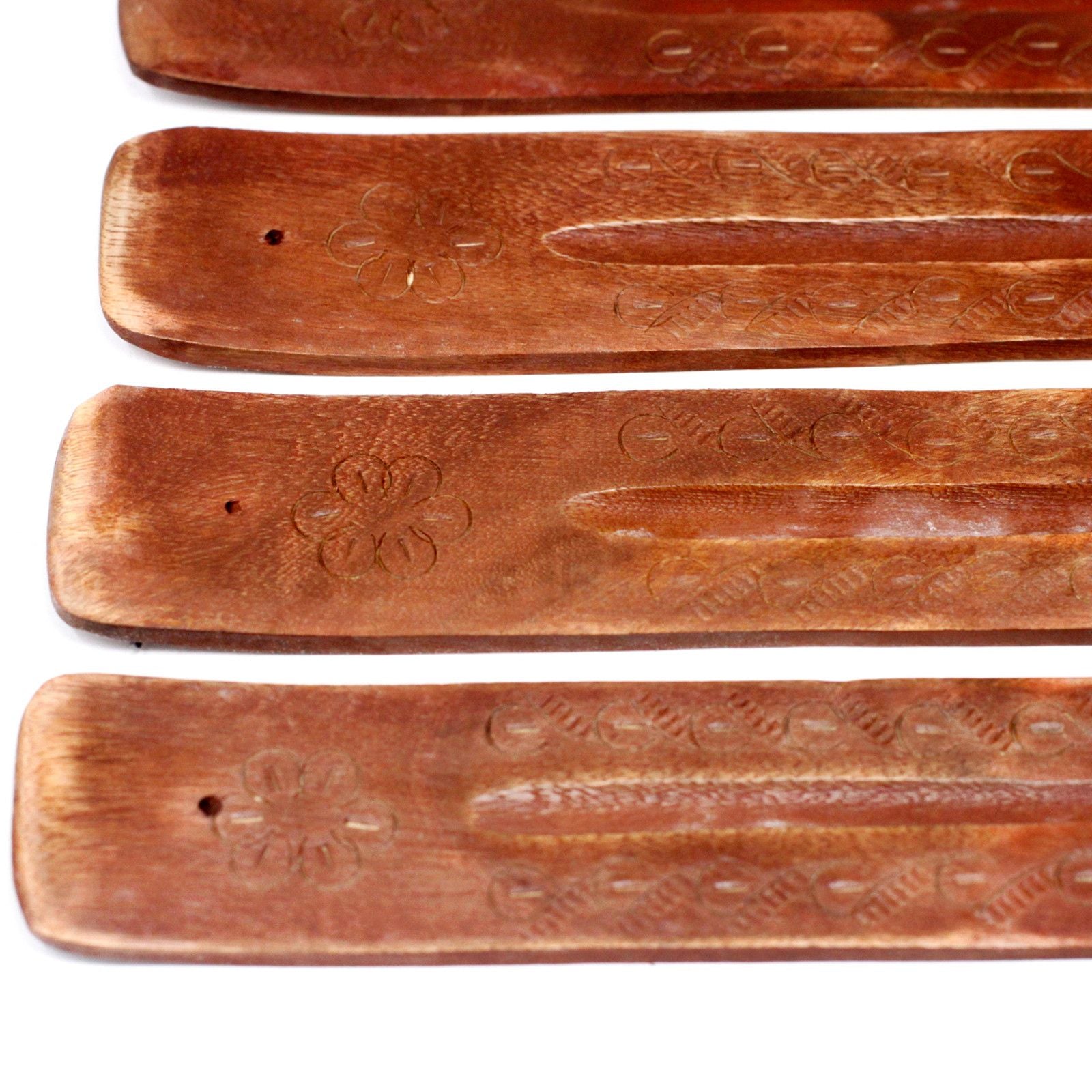 Set of four wooden incense holders with engraved designs on a white background