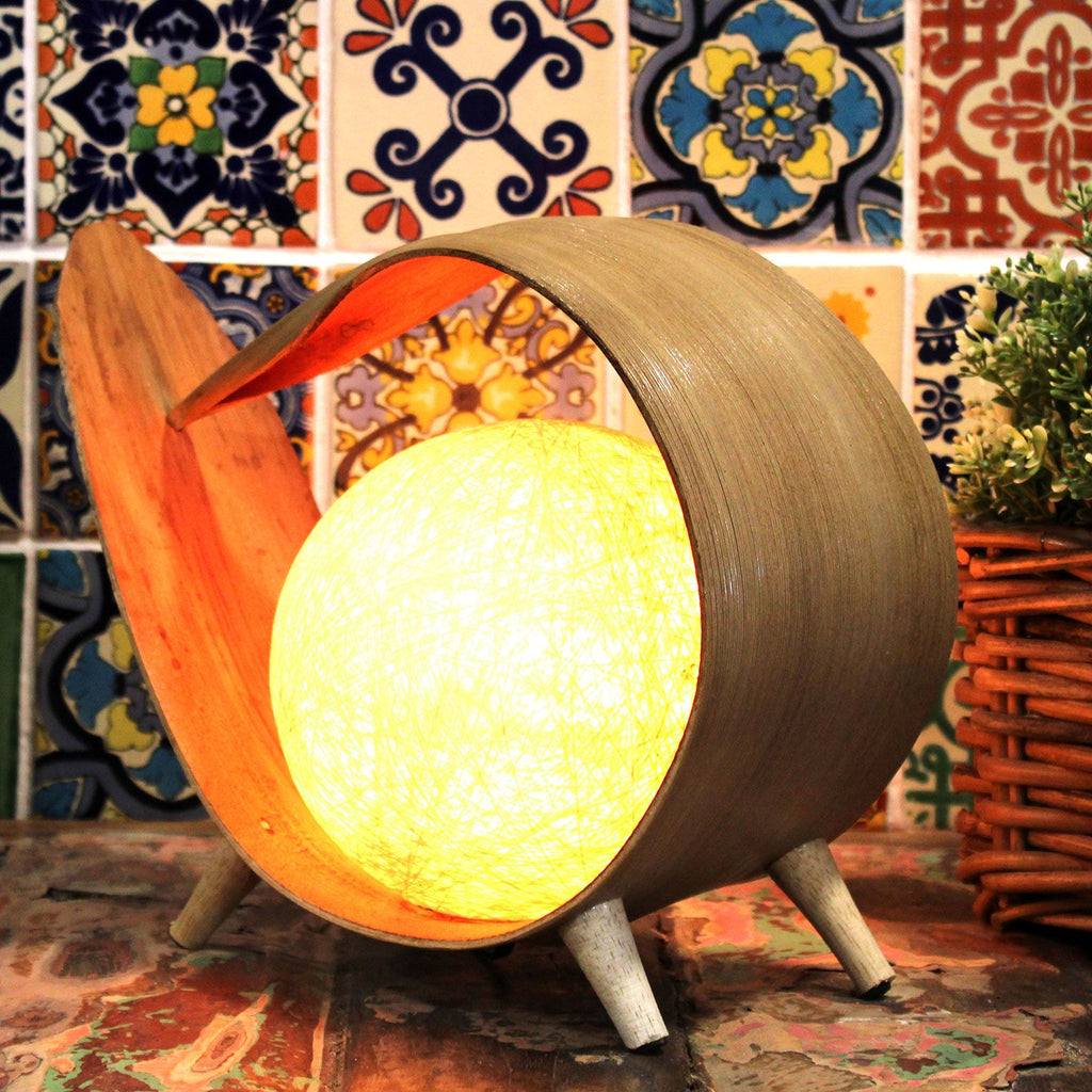 Decorative lamp with a warm glow against a colourful tile wall.