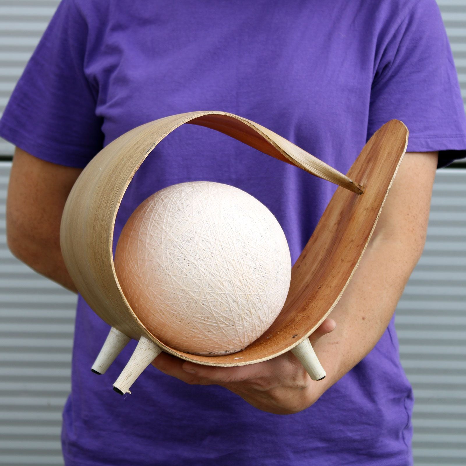 Person holding a wooden coconut lamp