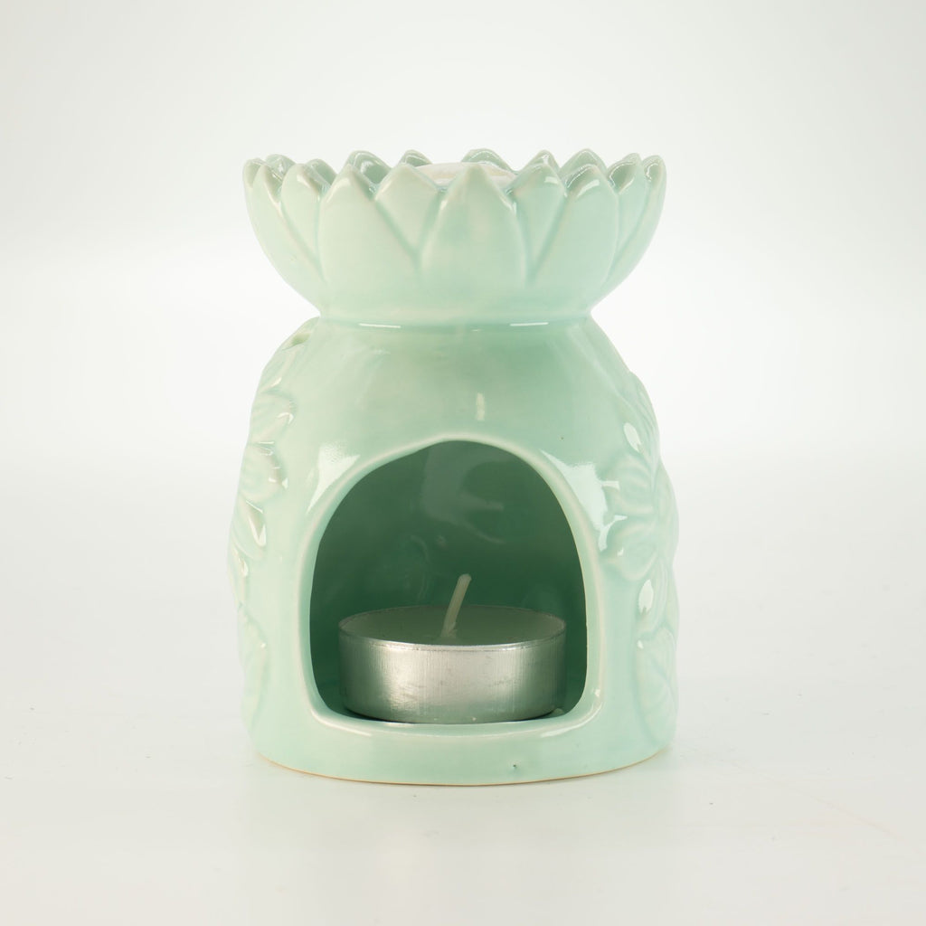 Mint green ceramic oil burner with a small candle inside on a white background