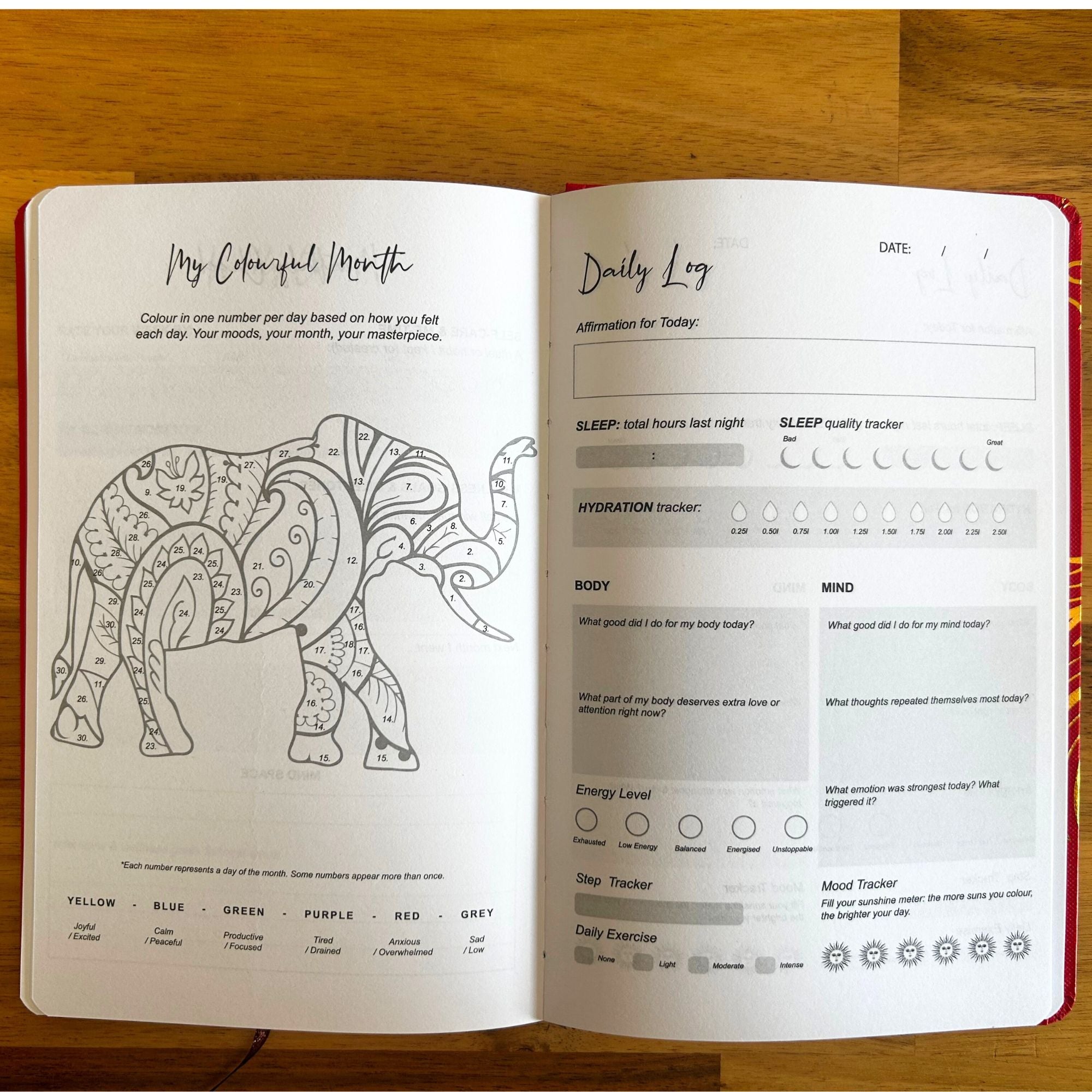 Open journal with colouring page of an elephant and daily log on a wooden surface